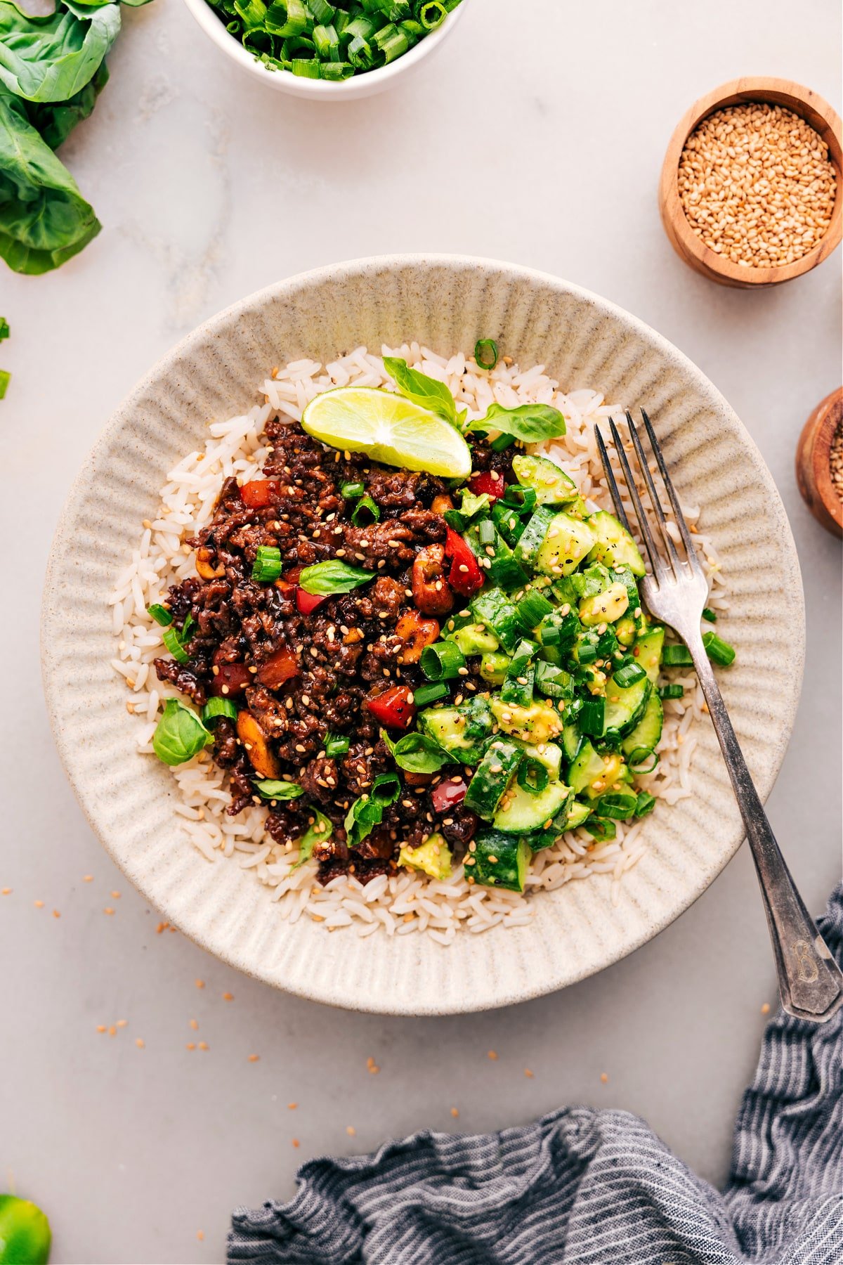 The Asian ground beef dish plated on a bed of rice, with a cucumber avocado salad on the side.