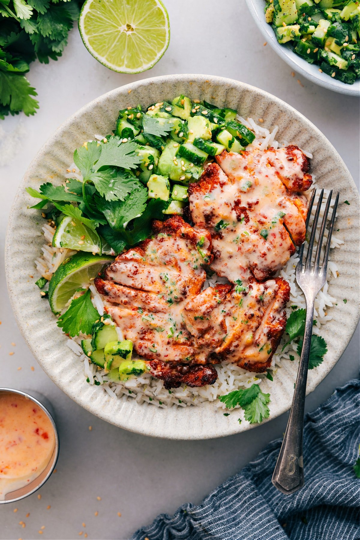 Bang Bang Chicken served on a bed of coconut rice, paired with a refreshing cucumber salad on the side.