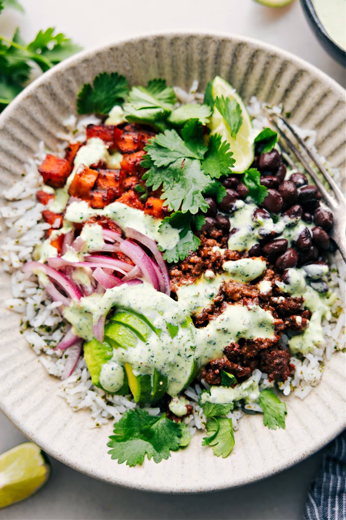 Beef burrito bowl recipe with cilantro lime sauce drizzled over it.