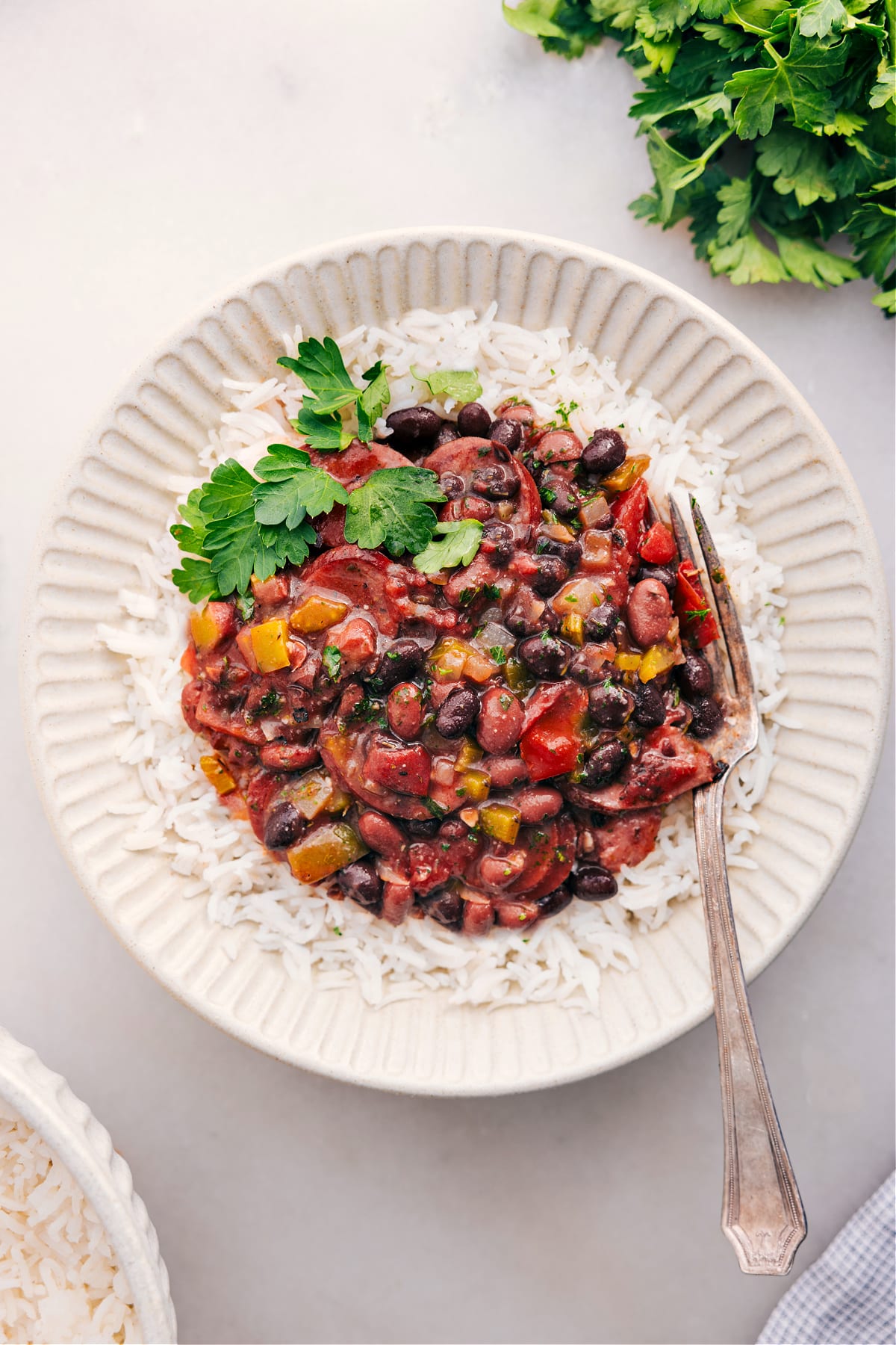 Black beans and sausage over rice with fresh herbs on top.