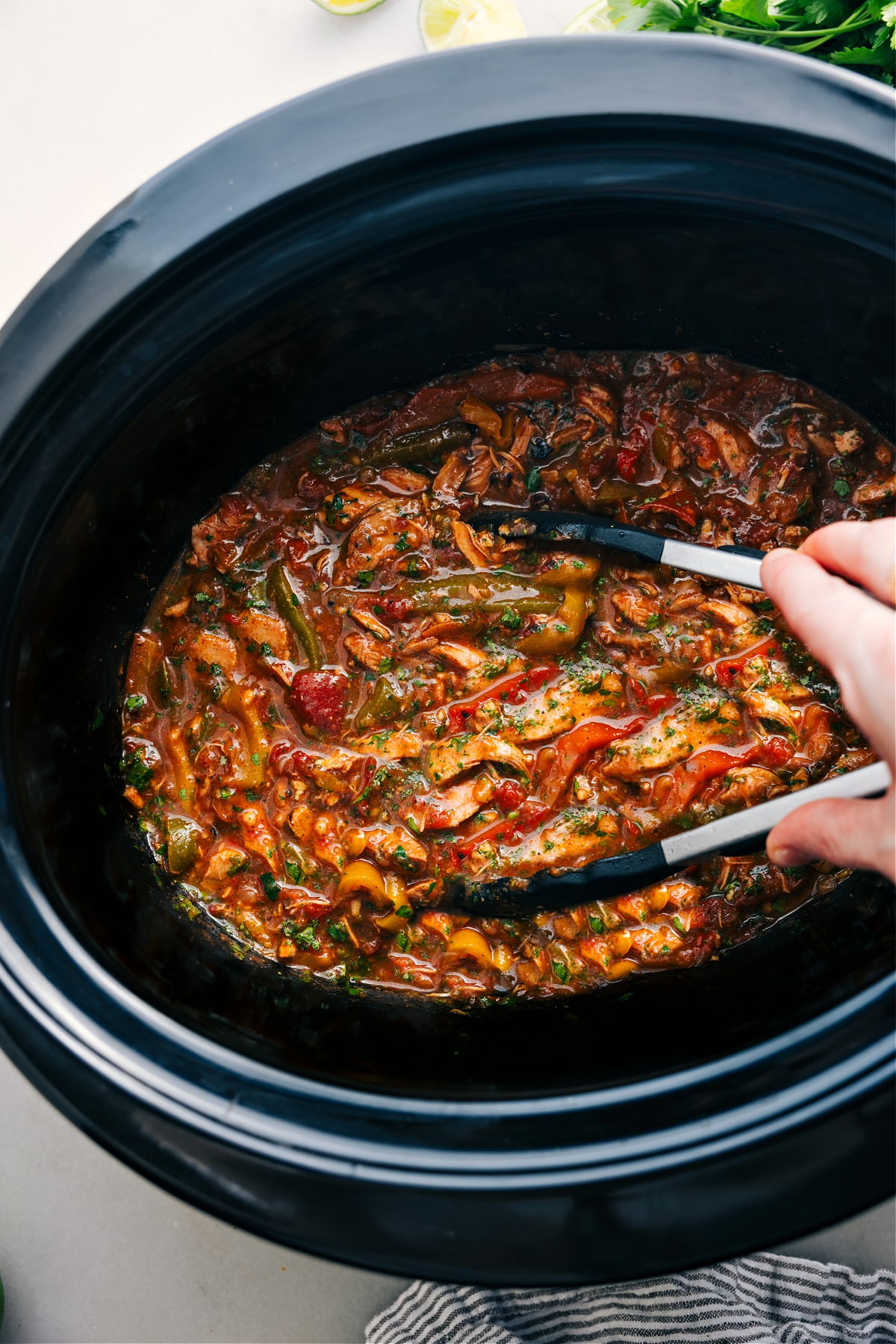 Crockpot Chicken Fajitas cooked in the slow cooker. Use tongs to serve.