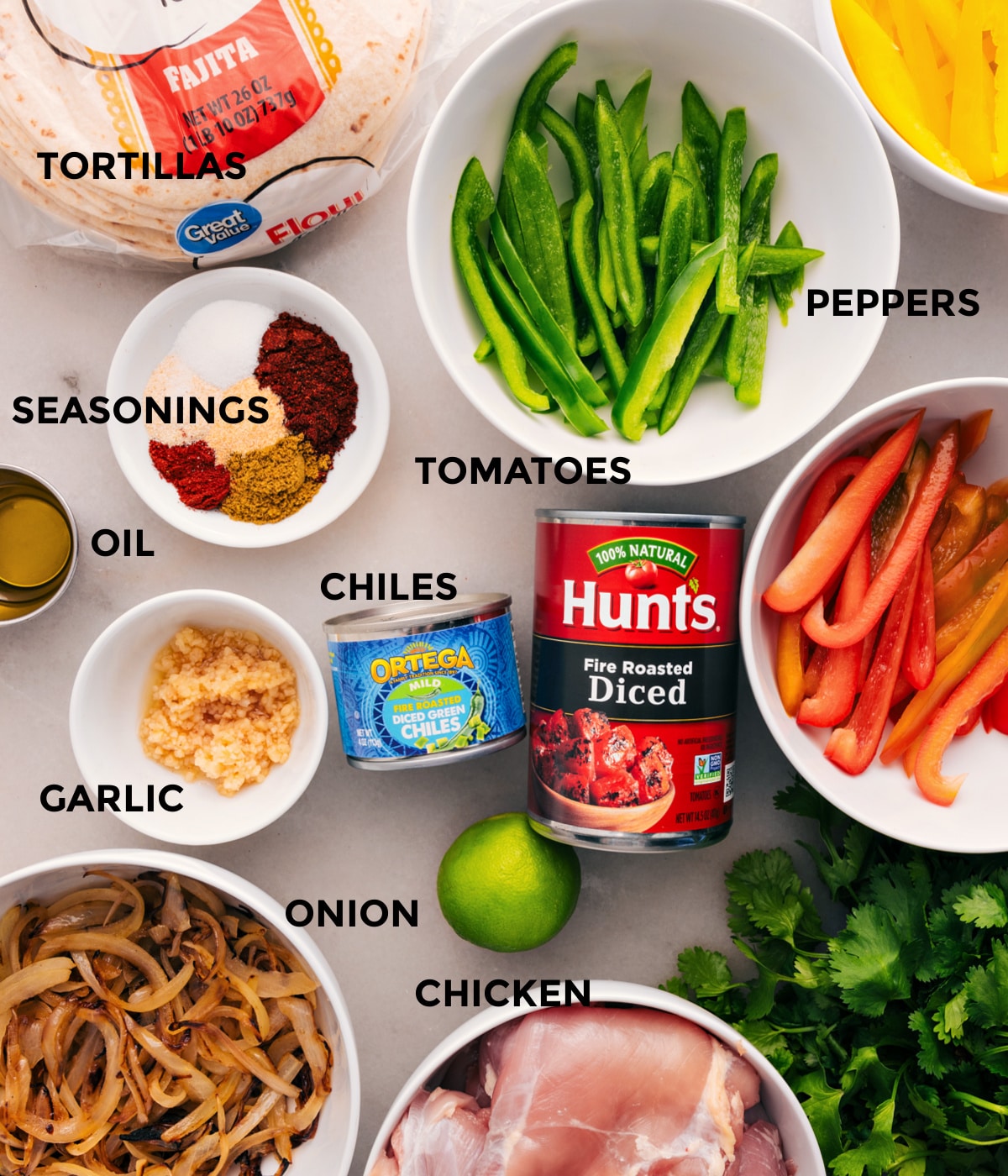 All the ingredients for this dish are prepped for easy assembly: peppers, meat, tomatoes, chiles, garlic, seasonings, tortillas, onions, and limes.