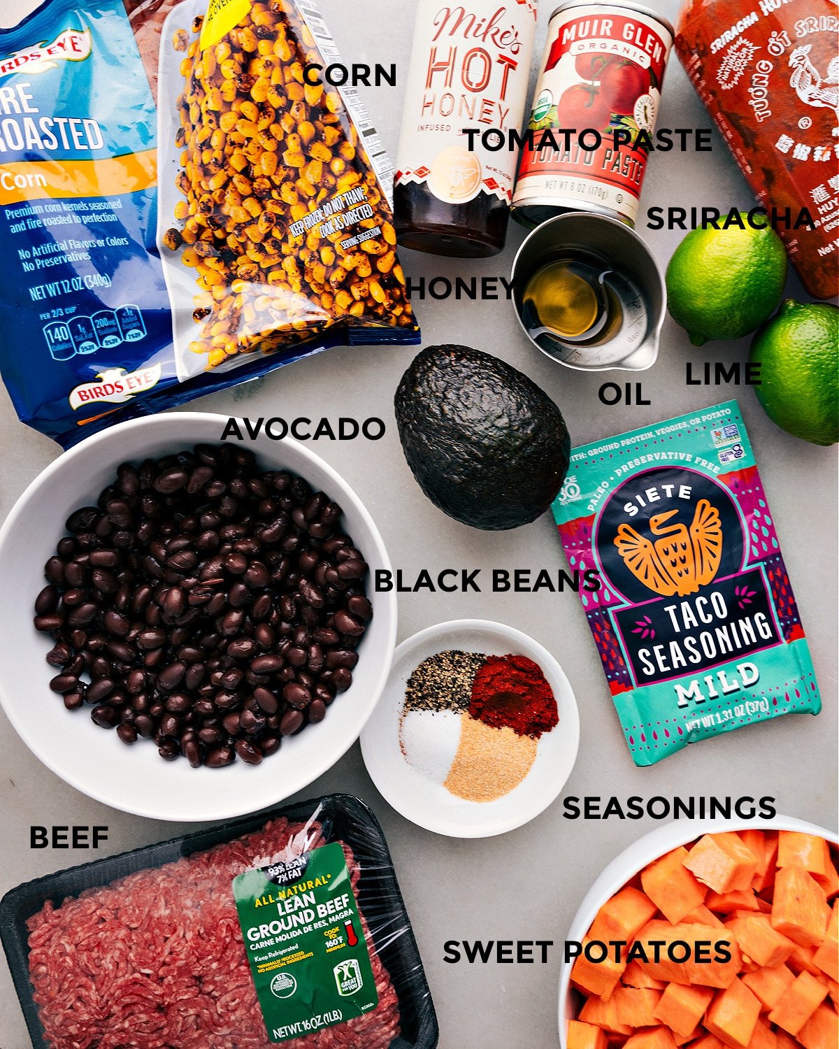 All the ingredients for this recipe are prepped and ready for easy assembly, including corn, hot honey, tomato paste, sriracha, lime, oil, avocado, seasonings, black beans, meat, and sweet potatoes.